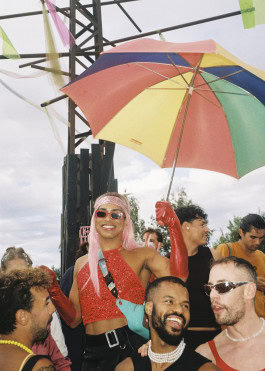 Person with rainbow umbrella smiles in crowd at Whole festival in Berlin 