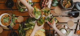 People clink glasses over a table of vegan food at Chay Long, Berlin