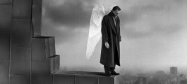Photo of a man with wings standing on the edge looking down 