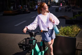 Woman on the street smiles and leans on a ebike