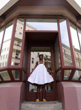 Model posing in a Buki Akomolafe, Quilt Dress near a building