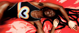 Black man posing lying down in one-piece swimsuit