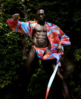Black man posing against greenery background dressed in swimming trunks and kimono from Effenberger Couture x Timo Gerber