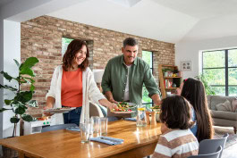 Happy smiling parents serving dinner to their kids 