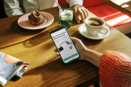 Woman in coffee shop holding phone with open N26 app 