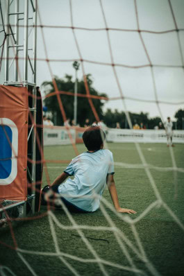 Boy sits on football field 