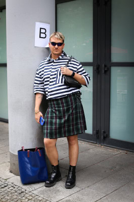 Man posing in a plaid kilt and striped T-shirt