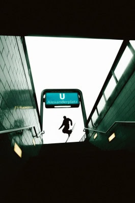 A man wearing sports equipment from Peak Performance Store Berlin and skis jumps at the top of an underground passage 
