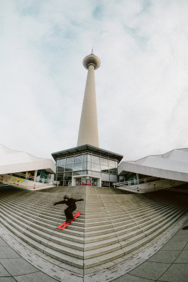 A man wearing sports equipment from Peak Performance Store Berlin skis down the steps on the street 