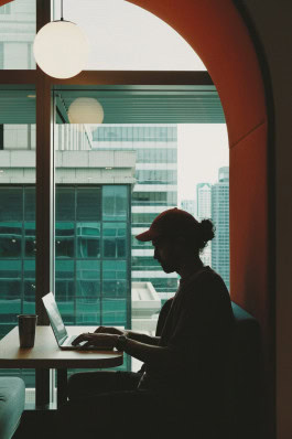 A woman sits with a laptop at a table 