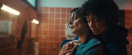 A still from the movie Highly Explosive where one woman hugs another from behind