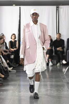 A female model of the MARKE brand in a white suit with a pink jacket walks the catwalk at Berlin Fashion Week