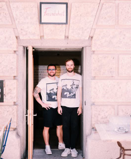 Two men smile at the entrance to the Freundschaft bar in Berlin 