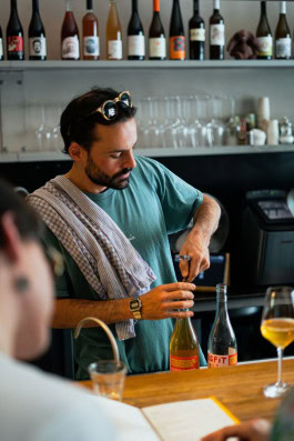 A bartender behind the bar opens a bottle of wine at The Rad bar in Berlin