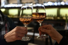 Two people clink glasses of white wine at the Mauerwinzer bar in Berlin