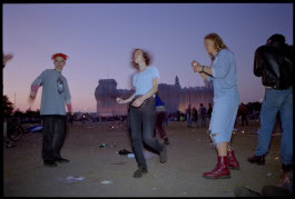 Blurry photo of a guy and two girls dancing at an outdoor party at dusk