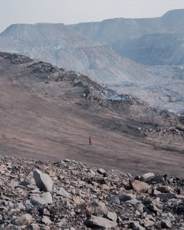 Man in red walks in rocky mountains