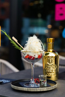 A cocktail at Dry Gin & Beef Club next to a bottle of gin