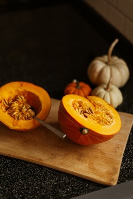 cut pumpkin on a cutting board, spoon inside 