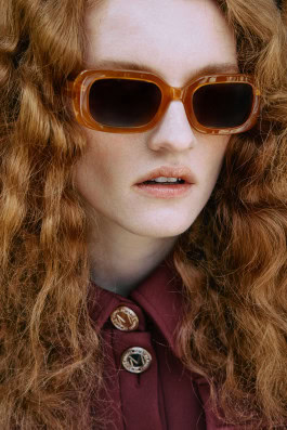 Redhead curly girl in burnt orange sunglasses 