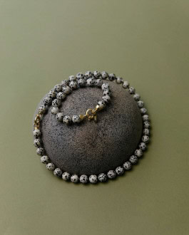 Necklace of white and black speckled stones on a round stone 