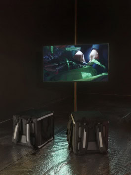 Photo by Alicja Rogalska, where there are two delivery backpacks on the floor and on the TV in front of them a man is zipping up the backpack 