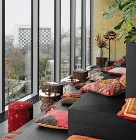 Monkey Bar seats with cushions and small tables facing large windows