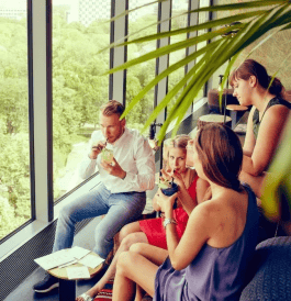 Monkey Bar people drink drinks in seats with cushions and small tables facing large windows