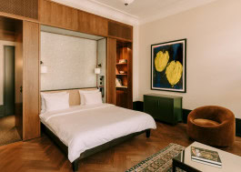 Château Royal hotel room interior, bed in niche, armchair and nightstands