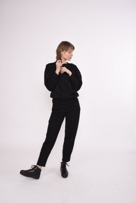 woman posing in black sweatshirt, black sweatpants and boots