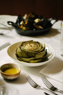 Le Petit Royal photo of the table, artichoke on a plate, cutlery and sauce next to it