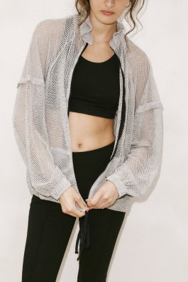 woman posing in black top, black leggings and mesh white jacket
