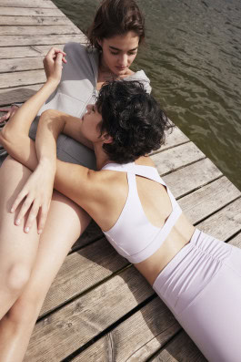 one woman lying on top of another on a pier in sportswear