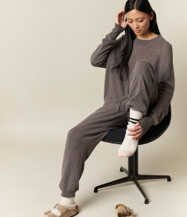 woman posing sitting on chair in grey t-shirt, grey sweatpants and beige sandals
