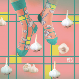 feet hanging in socks with a geometric pink print with yellow and turquoise lines and garlic, on a background repeating the print