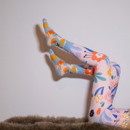 woman lying with her legs up in soft pink floral leggings and multicolored socks